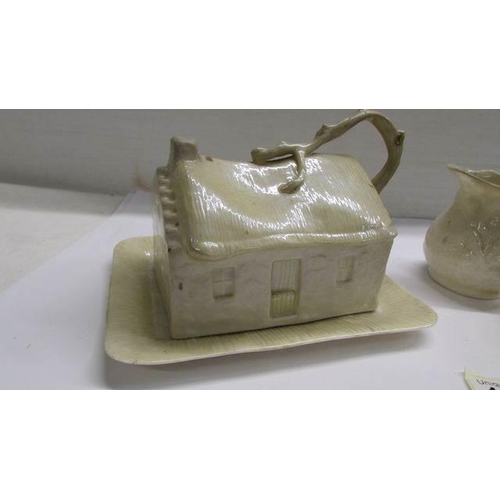 1242 - A Belleek butter dish in the form of a cottage together with a Belleek milk jug and sugar bowl.