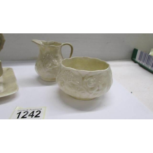 1242 - A Belleek butter dish in the form of a cottage together with a Belleek milk jug and sugar bowl.