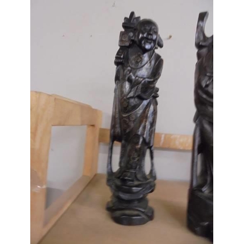 1303 - A pair of carved oriental figures with brass string inlay, 29 cm tall.