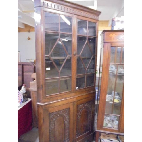 1413 - An oak astragal glazed corner cupboard with carved doors.