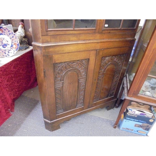 1413 - An oak astragal glazed corner cupboard with carved doors.