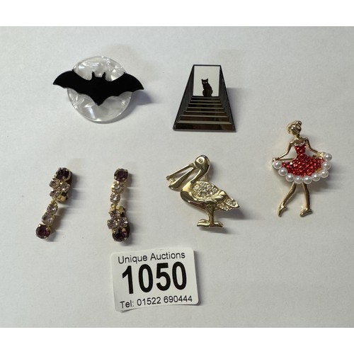 1050 - Four assorted brooches including pelican, bat, ballerina and a pair of clip on earrings.