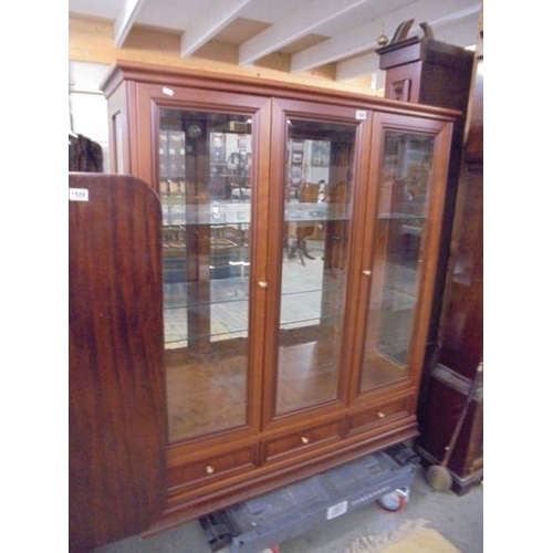 1560 - A darkwood finished display cabinet with three bevelled glass doors and 3 drawers.