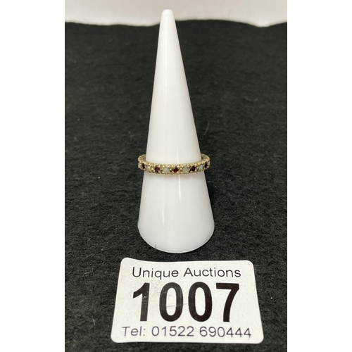 1007 - A 9ct gold eternity ring with red stone and opal settings (total weight 2.28g)