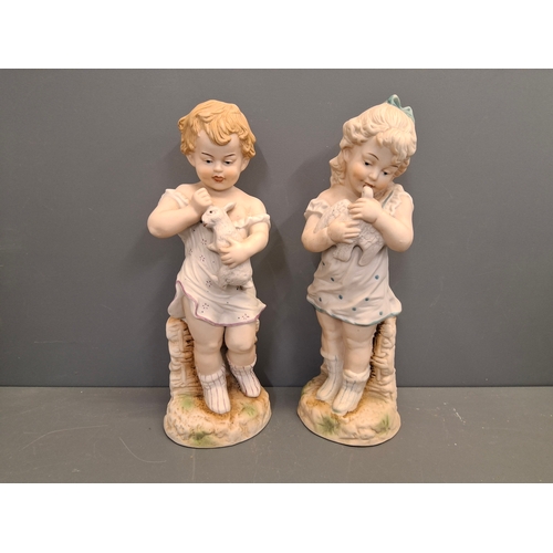 10 - A pair of Bisque porcelain figures. 
Measuring 33cm high