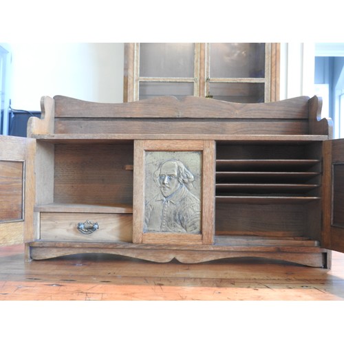 30 - AN OAK FITTED TABLE TOP CABINET DECORATED WITH BRASS EMBOSSED PANELS DEPICTING SHAKESPEARE, two door... 