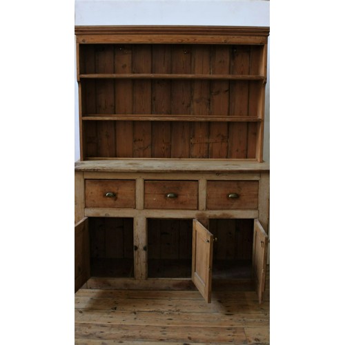 12 - A RUSTIC PINE THREE DOOR KITCHEN DRESSER WITH 3-TIER PLATE RACK, the base comprised of three deep dr... 