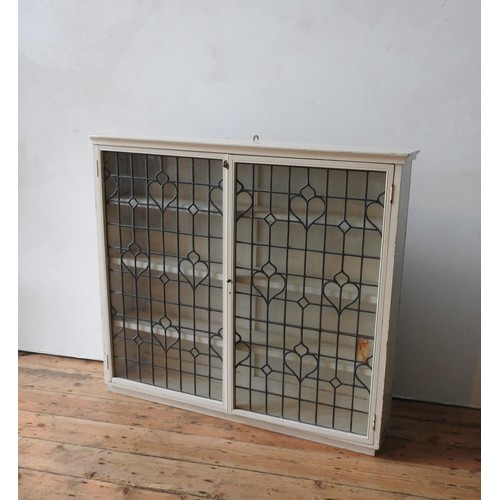 18 - A CREAM PAINTED LEADED LIGHT TWO DOOR BOOKCASE, with three interior shelves, 113 x 126 x 24cm