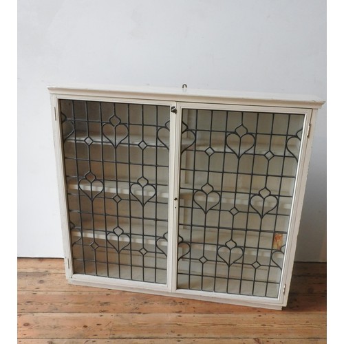 18 - A CREAM PAINTED LEADED LIGHT TWO DOOR BOOKCASE, with three interior shelves, 113 x 126 x 24cm