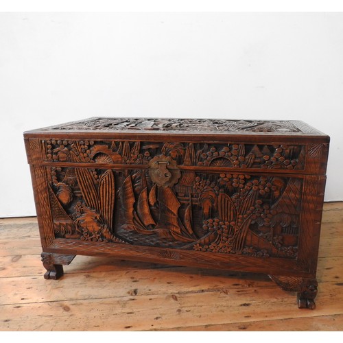 34 - AN ORNATE CARVED CAMPHORWOOD BLANKET CHEST , with two carved handles and claw feet,  62 x 98 x 54 cm