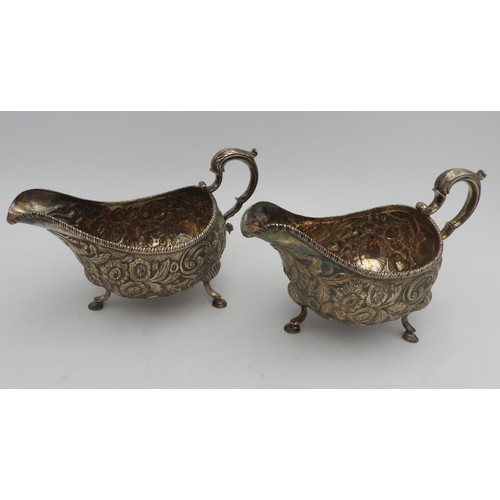 318 - A PAIR OF IRISH HALLMARK SILVER SAUCEBOATS, with ornate floral embossed decoration with ornate scrol... 