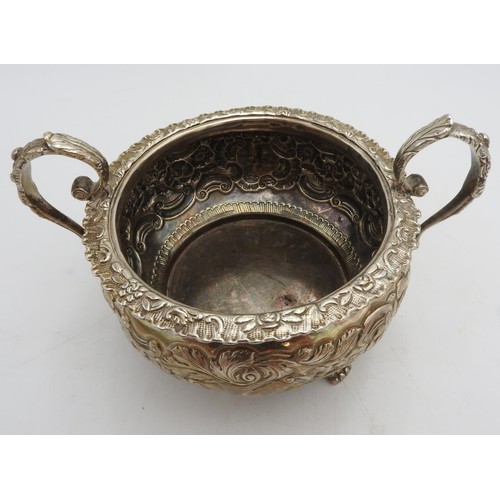 321 - AN ORNATE IRISH HALLMARK SILVER BOWL WITH TWO HANDLES, embossed with ornate floral design, two scrol... 