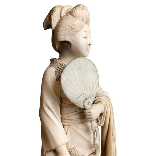 325 - JAPANESE IVORY OKIMONO OF A GEISHA, MEIJI PERIODthe geisha holding a fan, her other hand lifting her... 