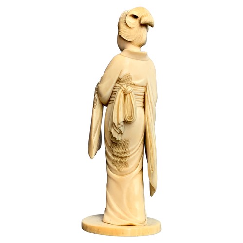 325 - JAPANESE IVORY OKIMONO OF A GEISHA, MEIJI PERIODthe geisha holding a fan, her other hand lifting her... 