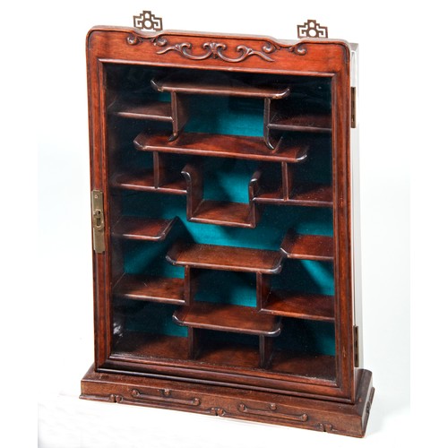 278 - CHINESE CARVED HARDWOOD WALL CABINET20TH CENTURYthe glazed panel door enclosing an arrangement of sh... 