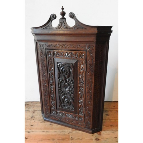 20 - A CONTINENTAL OAK 19TH CENTURY ORNATE CARVED CORNER CUPBOARD, with scroll and finial pediment and or... 