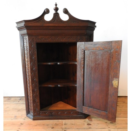 20 - A CONTINENTAL OAK 19TH CENTURY ORNATE CARVED CORNER CUPBOARD, with scroll and finial pediment and or... 