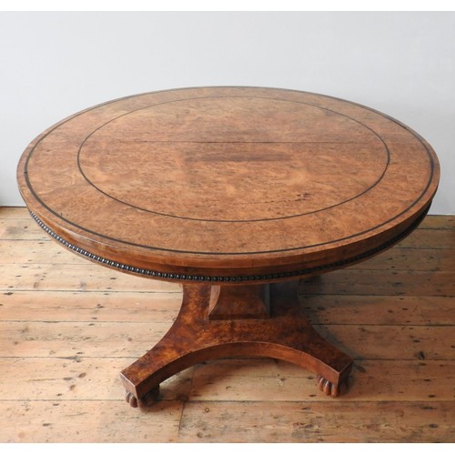 69 - A GEORGE IV BURR ELM CIRCULAR TOP DINING TABLE ON CARVED CENTRAL PEDESTAL, with a curved edge base o... 