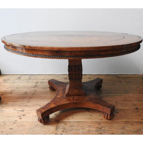 69 - A GEORGE IV BURR ELM CIRCULAR TOP DINING TABLE ON CARVED CENTRAL PEDESTAL, with a curved edge base o... 