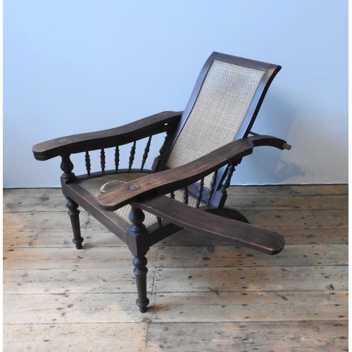 75 - A HARDWOOD RATTAN PANELLED LOLLING CHAIR, with adjustable pegged back and swivel support panels bene... 