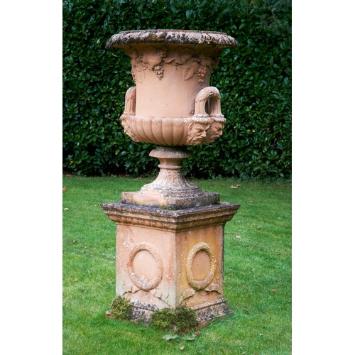 96 - LARGE GARDEN STONEWARE URN20TH CENTURYof campana form, with Bacchic relief decoration, raised on a s... 