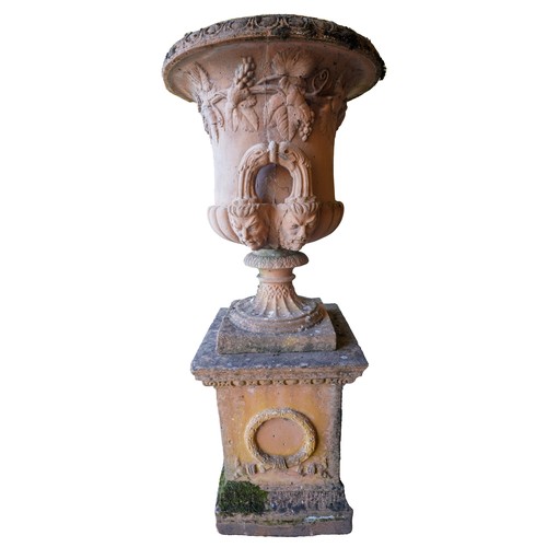 96 - LARGE GARDEN STONEWARE URN20TH CENTURYof campana form, with Bacchic relief decoration, raised on a s... 