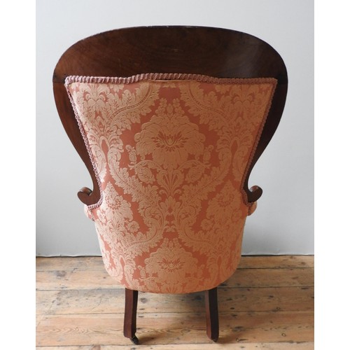 54 - A VICTORIAN MAHOGANY NURSING CHAIR, with scroll carved spoon back, buttoned upholstery supported by ... 