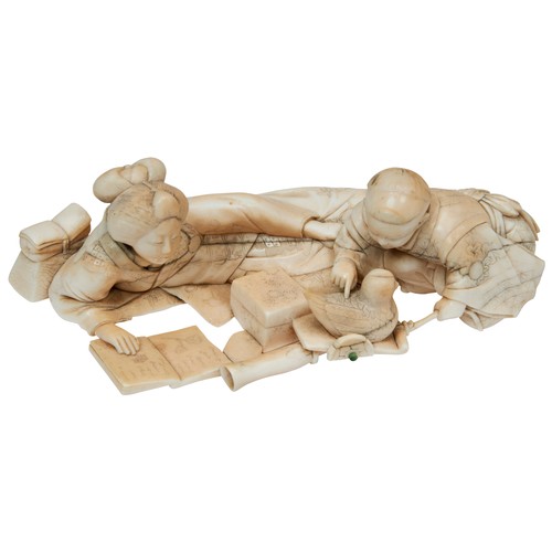 335 - A JAPANESE 19TH CENTURY IVORY OKIMONO OF A RECLINING MOTHER READING, her child playing next to her w... 