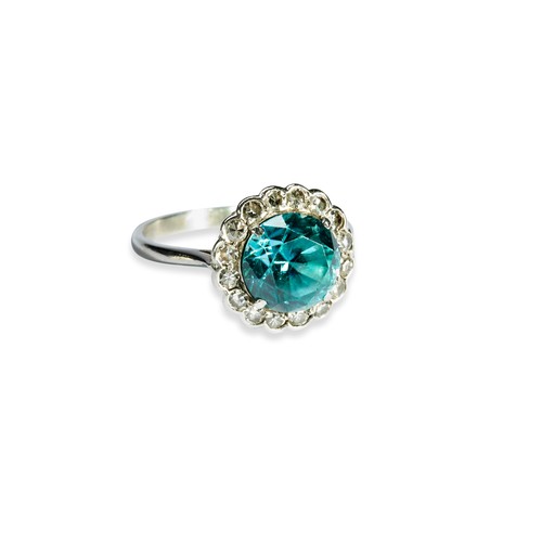 15 - A BLUE ZIRCON AND DIAMOND RING the circular-cut zircon, claw set within a bezel of sixteen brilliant... 