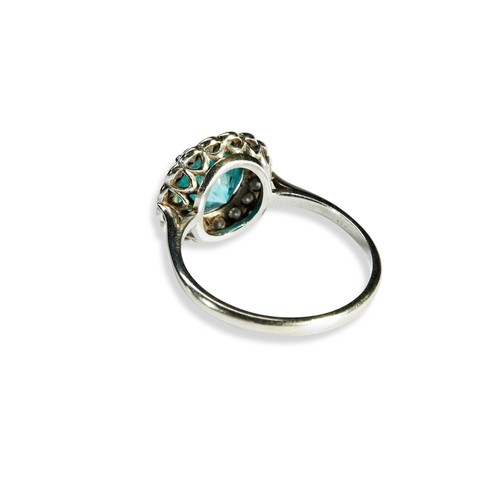 15 - A BLUE ZIRCON AND DIAMOND RING the circular-cut zircon, claw set within a bezel of sixteen brilliant... 