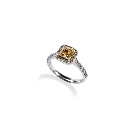 A FANCY INTENSE YELLOW DIAMOND RING the modified square brilliant-cut yellow diamond, weighing 1.02 carats four claw set above a square bezel set with sixteen white brilliant-cut diamonds, between diamond set shoulders, each set with a uniform row of six brilliant-cut diamonds, claw set. 