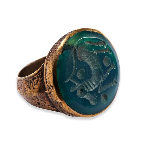 137 - AN INTAGLIO RING, the green Sasanian style seal stone cut with a stylised horse, in a polished bronz... 