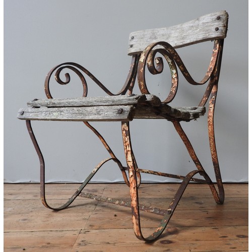 147 - A WROUGHT-IRON WOODEN SLATTED WEATHERED GARDEN ARMCHAIR, with curved seat, back panel and scroll arm... 