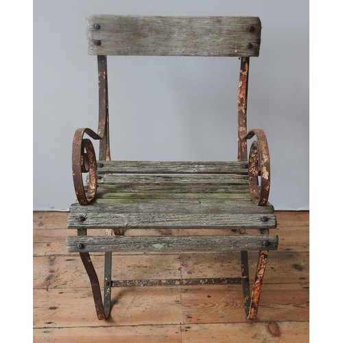 147 - A WROUGHT-IRON WOODEN SLATTED WEATHERED GARDEN ARMCHAIR, with curved seat, back panel and scroll arm... 