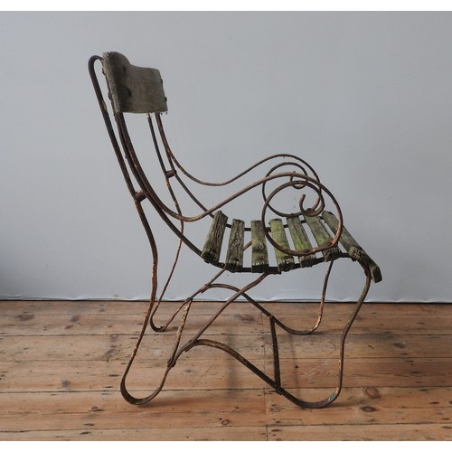 147 - A WROUGHT-IRON WOODEN SLATTED WEATHERED GARDEN ARMCHAIR, with curved seat, back panel and scroll arm... 