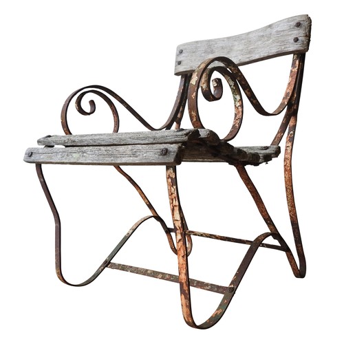 147 - A WROUGHT-IRON WOODEN SLATTED WEATHERED GARDEN ARMCHAIR, with curved seat, back panel and scroll arm... 