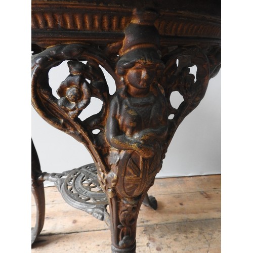 74 - A VINTAGE CAST-IRON PUB TABLE WITH CIRCULAR TOP, with Brittania decoration to the top of the legs, t... 