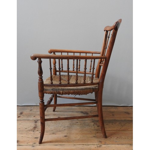 79 - A 19TH CENTURY RUSH SEAT ELBOW CHAIR, with a serpentine top rail supported by turned spindles, on fo... 