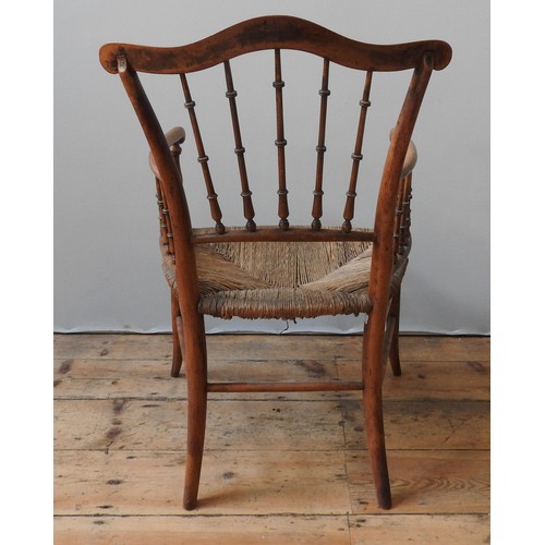 79 - A 19TH CENTURY RUSH SEAT ELBOW CHAIR, with a serpentine top rail supported by turned spindles, on fo... 