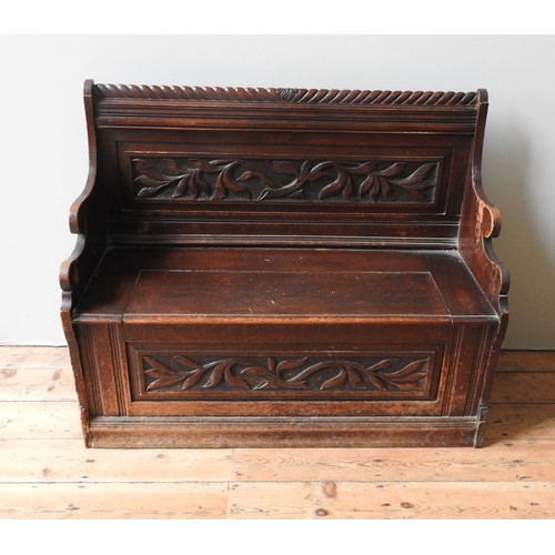 80 - A 19TH CENTURY OAK PEW / BENCH SEAT, with rope twist top rail, foliate carved back panel and lift-to... 