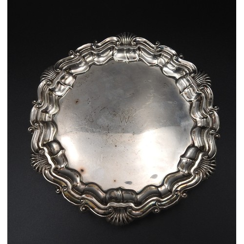 464 - A SILVER SALVER, with acanthus shell-scroll border on three scroll feet, London 1916, maker's mark G... 