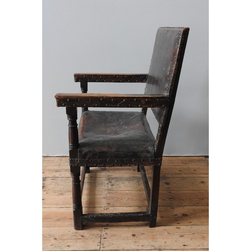 127 - A LARGE JAMES I LEATHER COVERED OAK ARMCHAIR, original lower carved stretcher rails