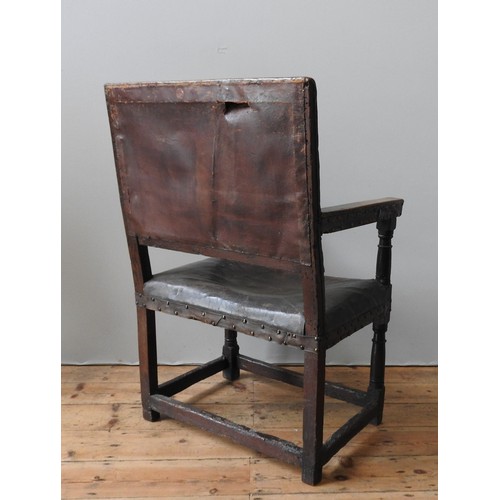 127 - A LARGE JAMES I LEATHER COVERED OAK ARMCHAIR, original lower carved stretcher rails