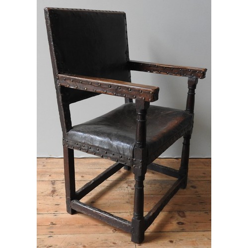 127 - A LARGE JAMES I LEATHER COVERED OAK ARMCHAIR, original lower carved stretcher rails