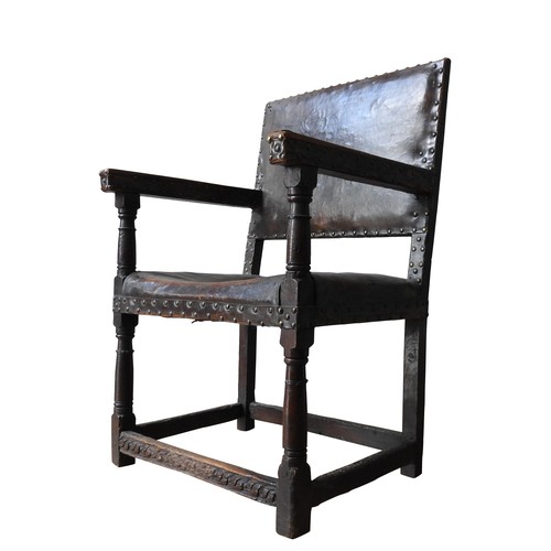 127 - A LARGE JAMES I LEATHER COVERED OAK ARMCHAIR, original lower carved stretcher rails