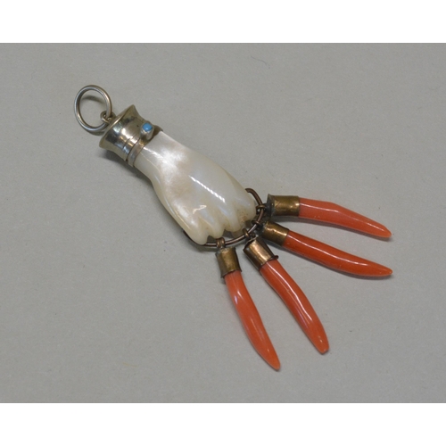 485 - A MOTHER OF PEARL AND CORAL FIGA PENDANT, with silver and turquoise mount, clutching four coral corn... 