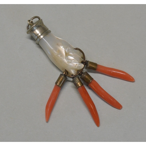 485 - A MOTHER OF PEARL AND CORAL FIGA PENDANT, with silver and turquoise mount, clutching four coral corn... 