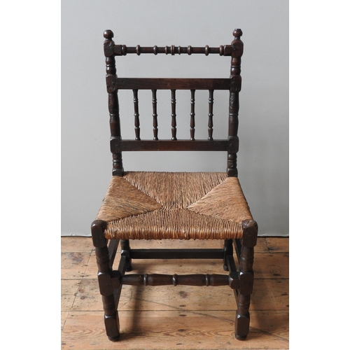 54 - AN 18TH CENTURY OAK RUSH SEAT CHAIR, with a turned top rail, turned spindle back,. on four turned le... 