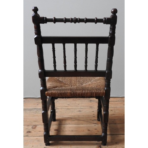 54 - AN 18TH CENTURY OAK RUSH SEAT CHAIR, with a turned top rail, turned spindle back,. on four turned le... 