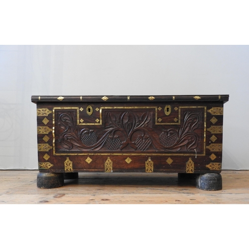 106 - A CARVED HARDWOOD EASTERN STORAGE TRUNK, with decorative brass mounts and banding throughout, the fr... 